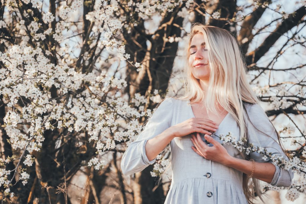 Woman in blue dress hands to chest smiling slighting and taking a breath. Photo by Eugene Zhyvchik on Unsplash