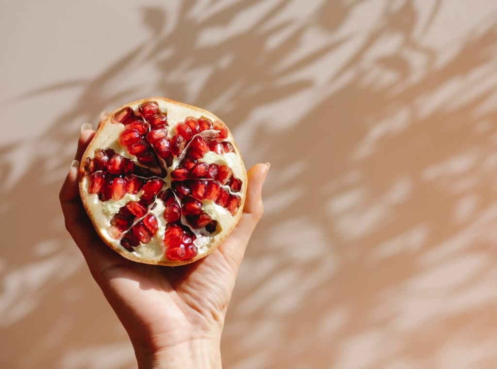 person holding a healthier snack, pomegranates 