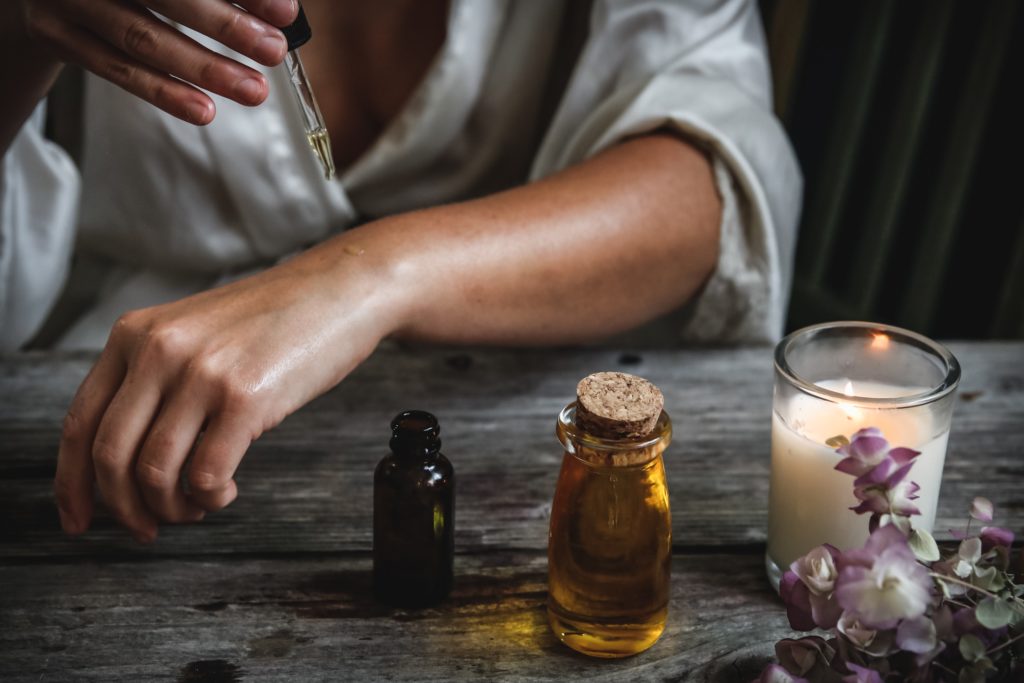 Woman applying essential oil onto the skin, diluted with a carrier oil. 