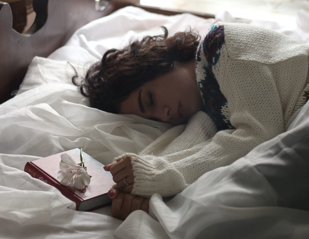 Woman sleeping with a book beside her.