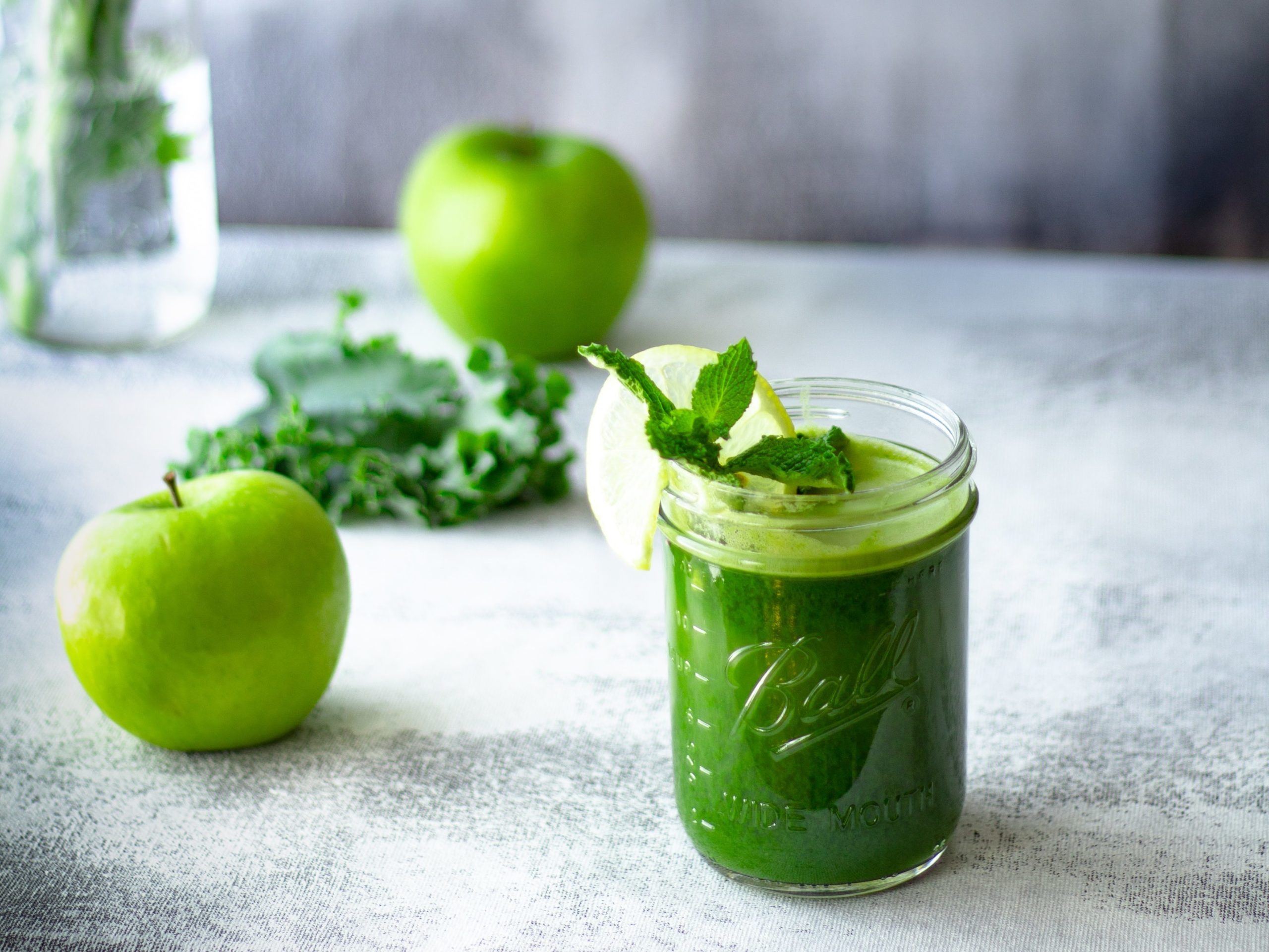 green juice smoothie in a clear glass jar..