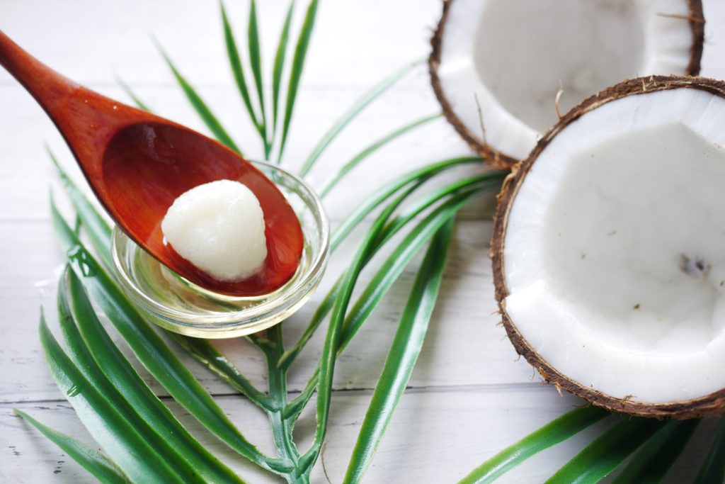 coconut oil, solid, on a spoon, beside coconuts