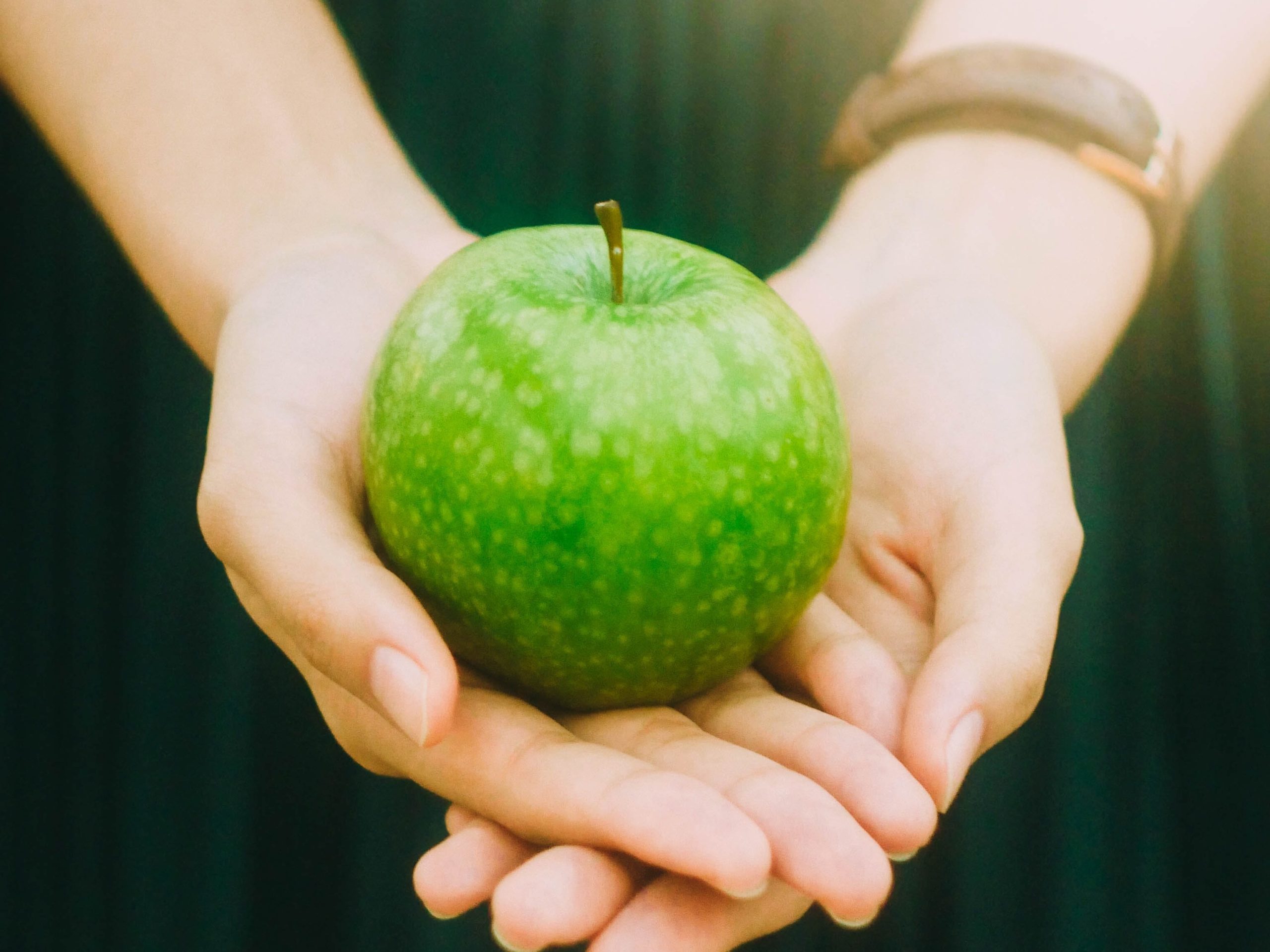 Person holding a green apple