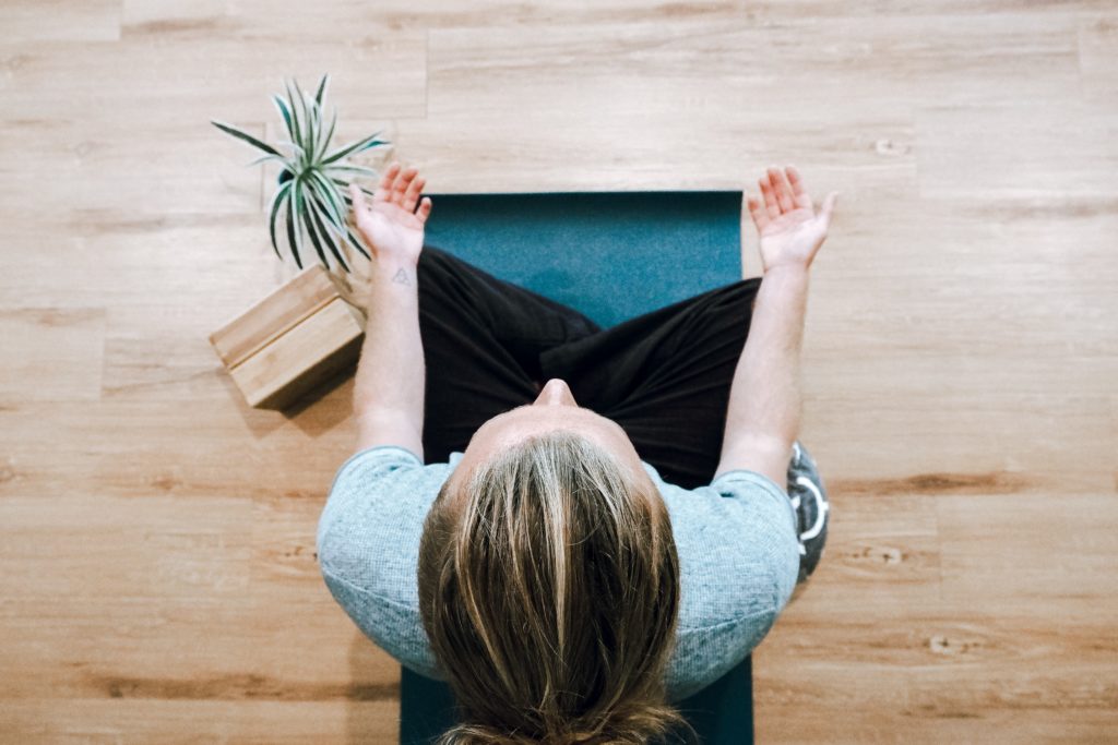 Person sitting on the ground cross-legged and meditating.