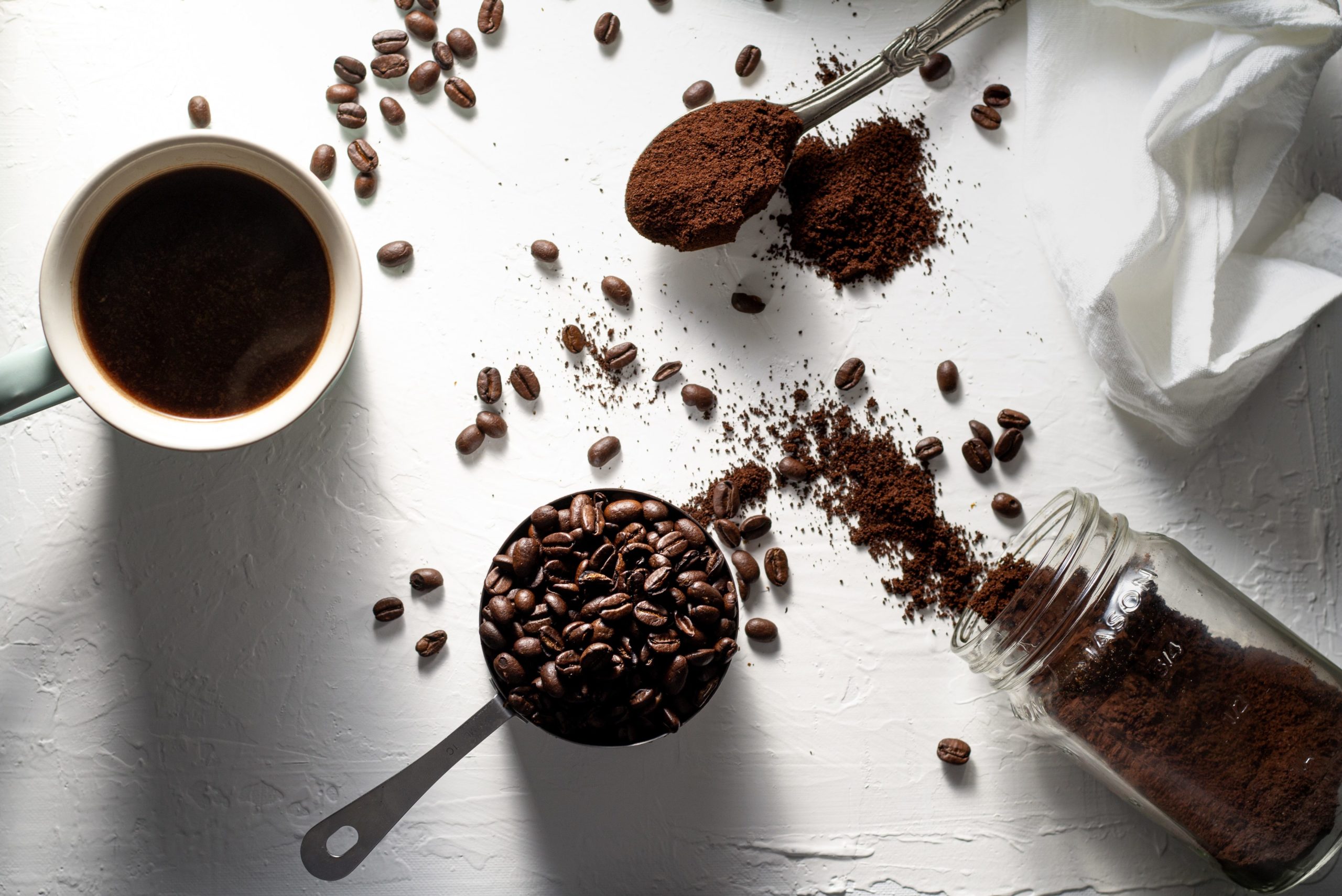 Picture of coffee cup, coffee beans, and freshly ground coffee. 