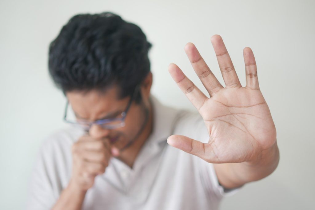 Person covering their mouth to cough.