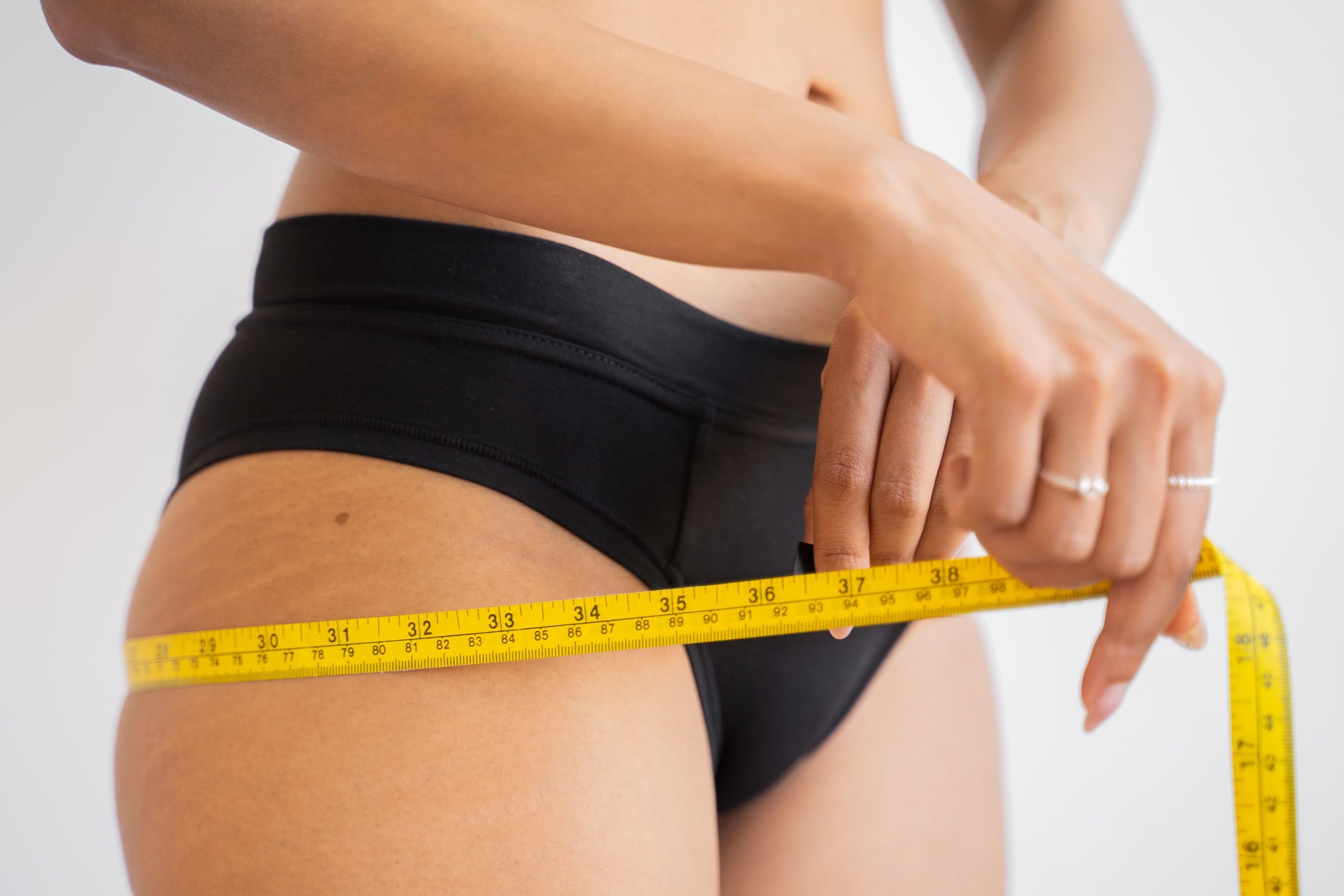 person measuring hips and belly fat