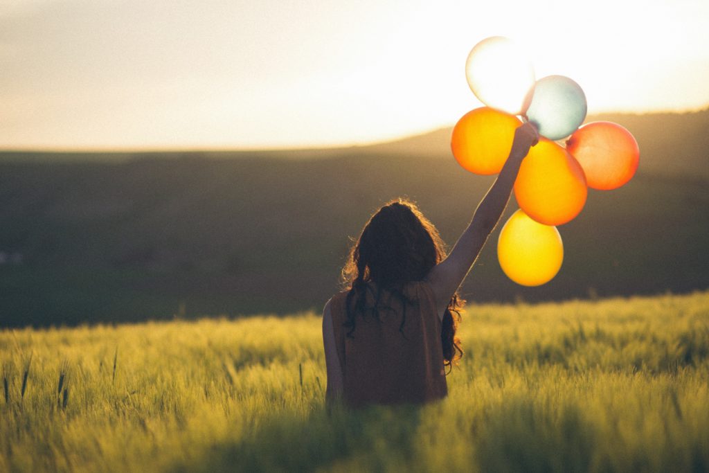 person holding balloons in a feild. 