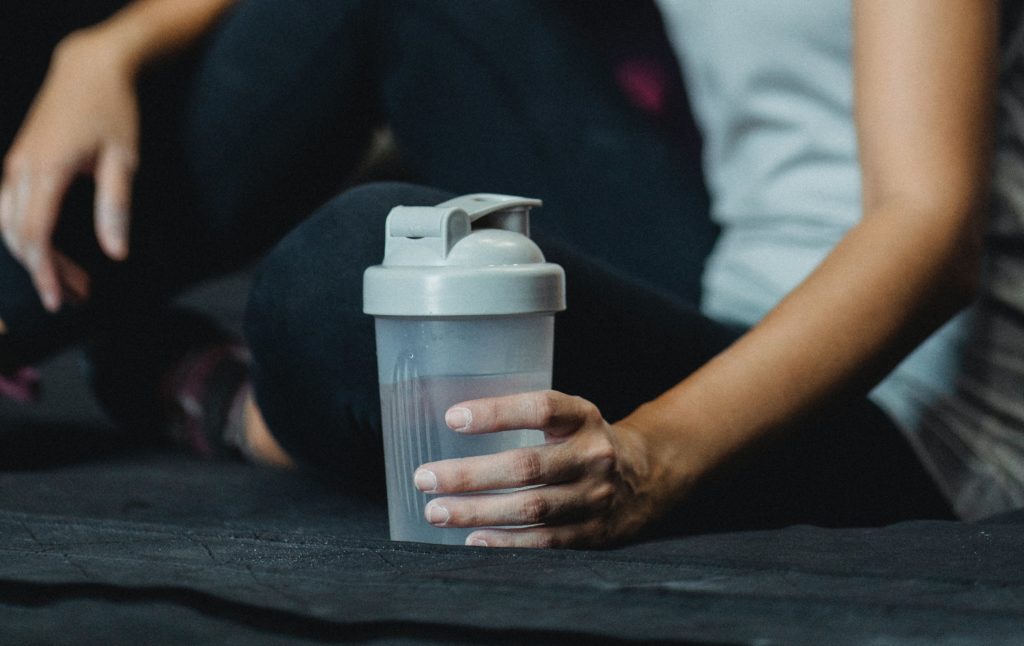 person about to drink creatine in water before a workout