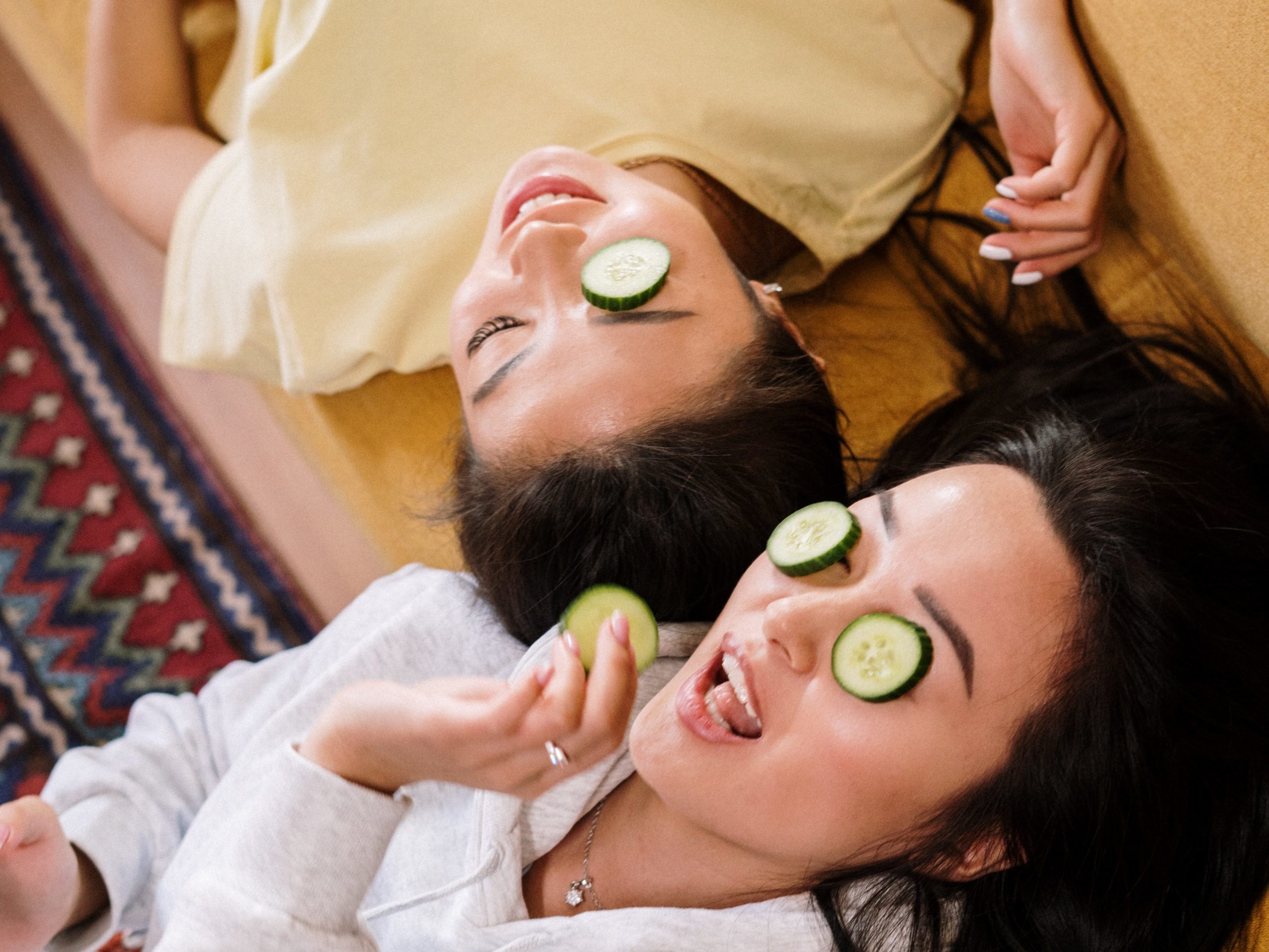 2 girls lying down, cucumber slices on the eyes, doing skincare for better skin